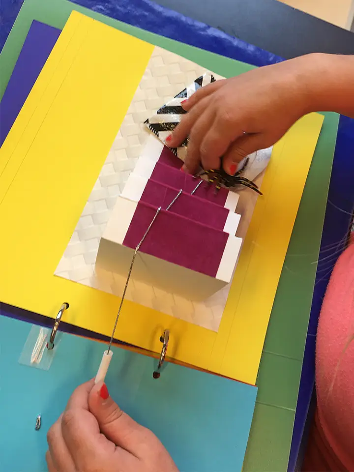 A student tests a prototype pop-up illustration of a staircase.