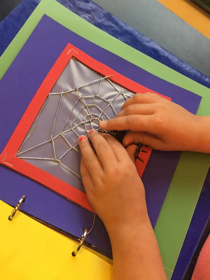 A student uses both hands to feel an illustration of a spider web.