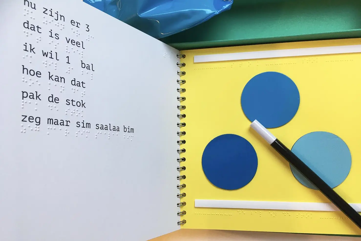 Double spread showing braille with print, a tactile illustration of three balls and a magic stick.